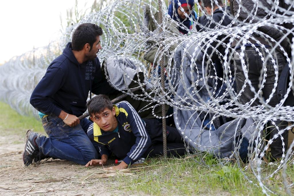 Profughi siriani al confine ungherese, segnato da un lungo muro di filo spinato, nel 2015
