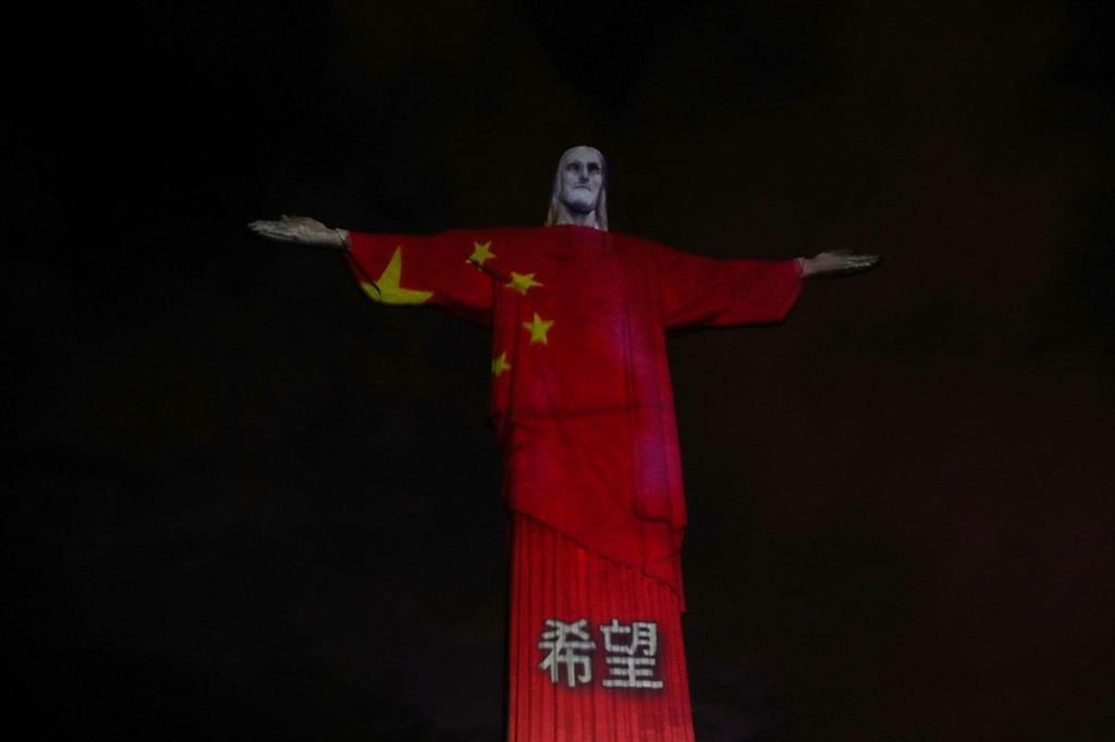 Le luci proiettano sulla statua la bandiera della Cina, il primo Paese a fare i conti con la pandemia - Reuters