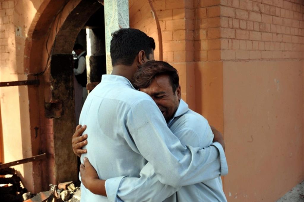 L'abbraccio tra due cristiani pakistani dopo l'incendio della loro chiesta