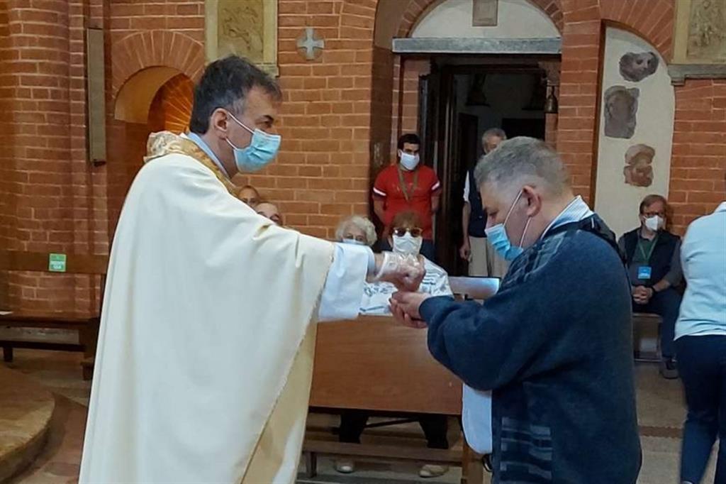 Don Franco Amati, parroco di Santa Maria Rossa nella periferia di Milano, è stato in fin di vita per il Covid. Nella foto mentre dà la Comunione a un fedele, contagiato e ormai guarito