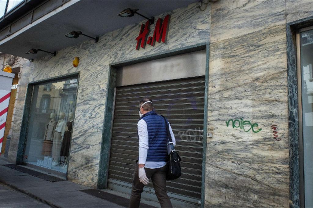 Un uomo passa davanti alla vetrina di H&M di via Torino, a Milano, negozio chiuso definitivamente a causa della crisi