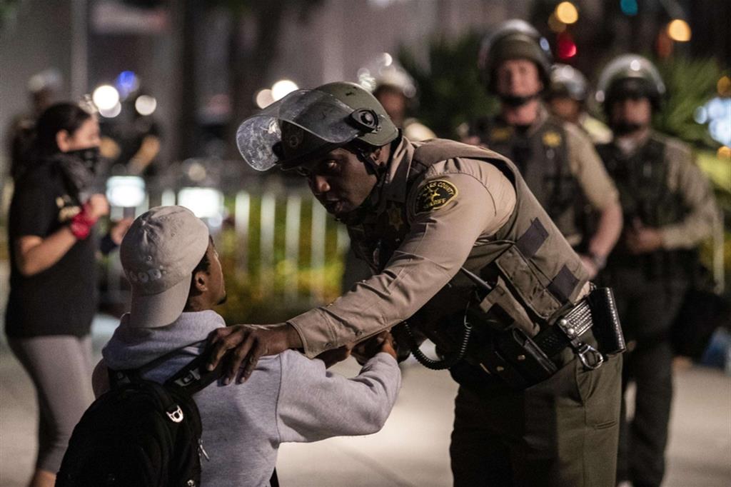 Un agente parla con un dimostrante che sta per essere arrestato per non aver rispettato il coprifuoco, davanti al municipio di Los Angeles