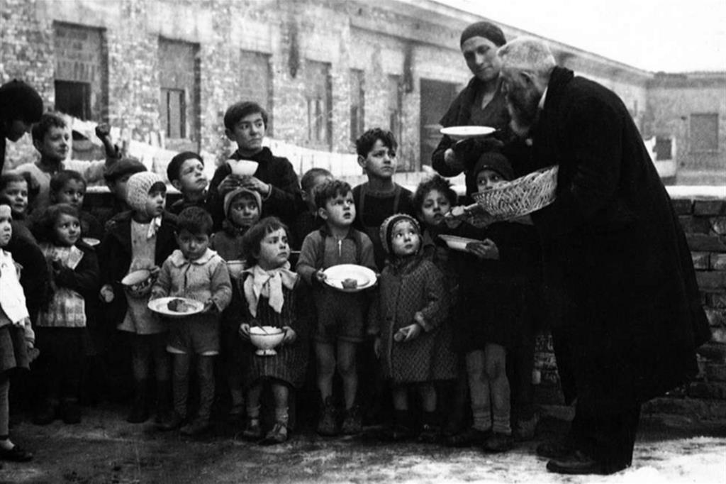 Don Marella (primo a destra) mentre distribuisce il pranzo a dei bambini bolognesi