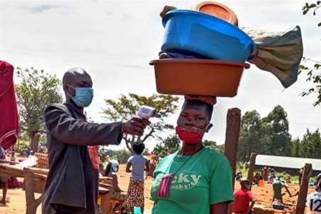 Un operatore di comunità misura la temperatura a una donna al mercato nel Rhino Camp in Uganda