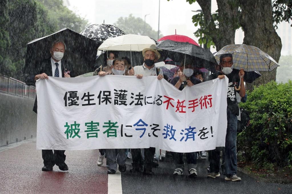 Una vittima di sterilizzazione (secondo da sinistra), manifesta con i suoi avvocati