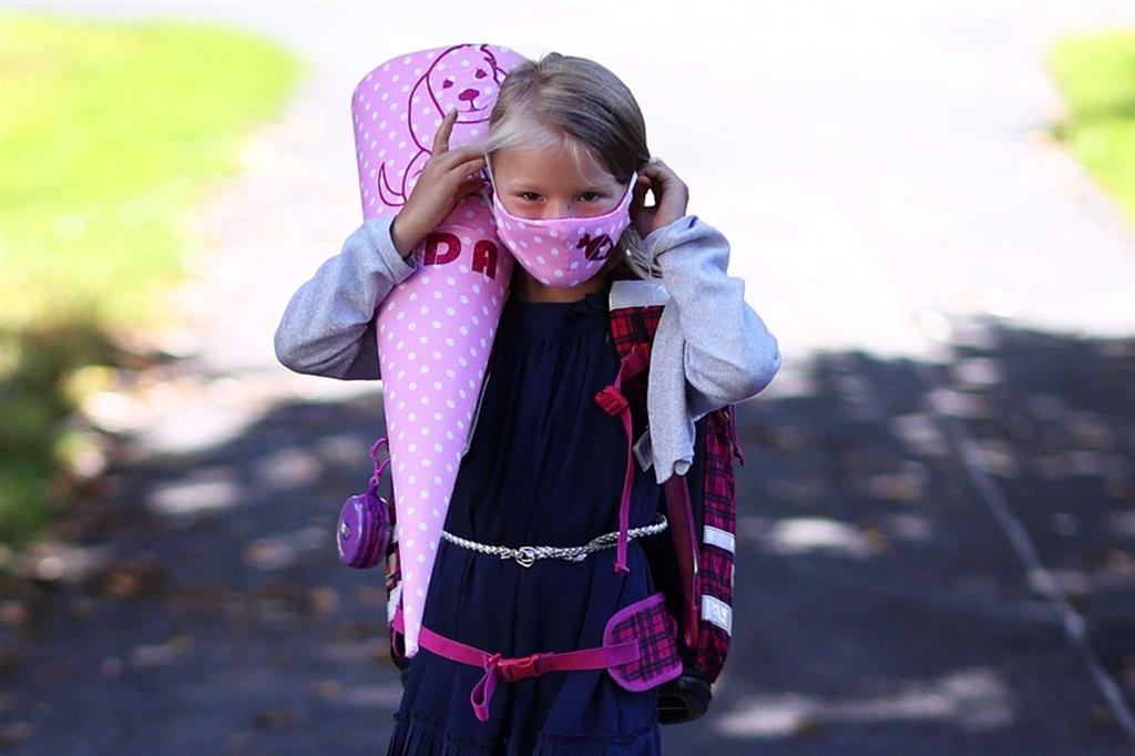 Una bimba tedesca va a scuola con la mascherina