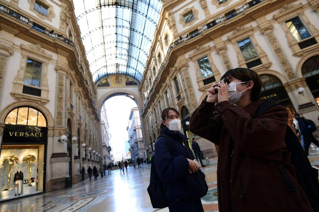 Turisti asiatici con la mascherina in Galleria Vittorio Emanuele, semideserta, a Milano