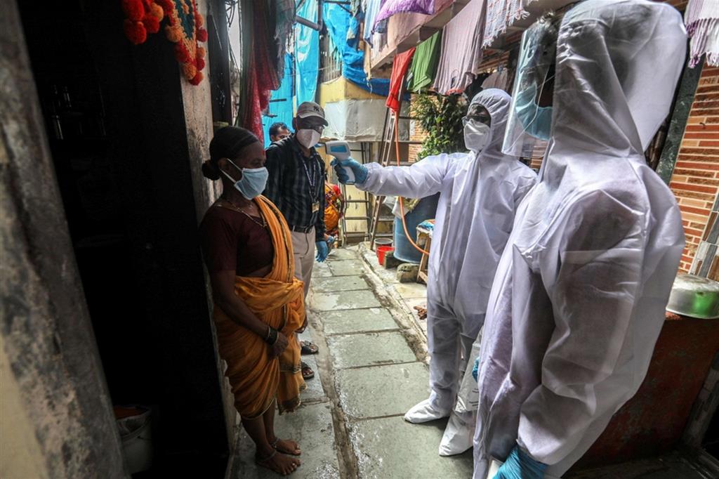 Operatori sanitari misurano la temperatura agli abitanti del quartiere focolaio di Appa Pada a Mumbai, India
