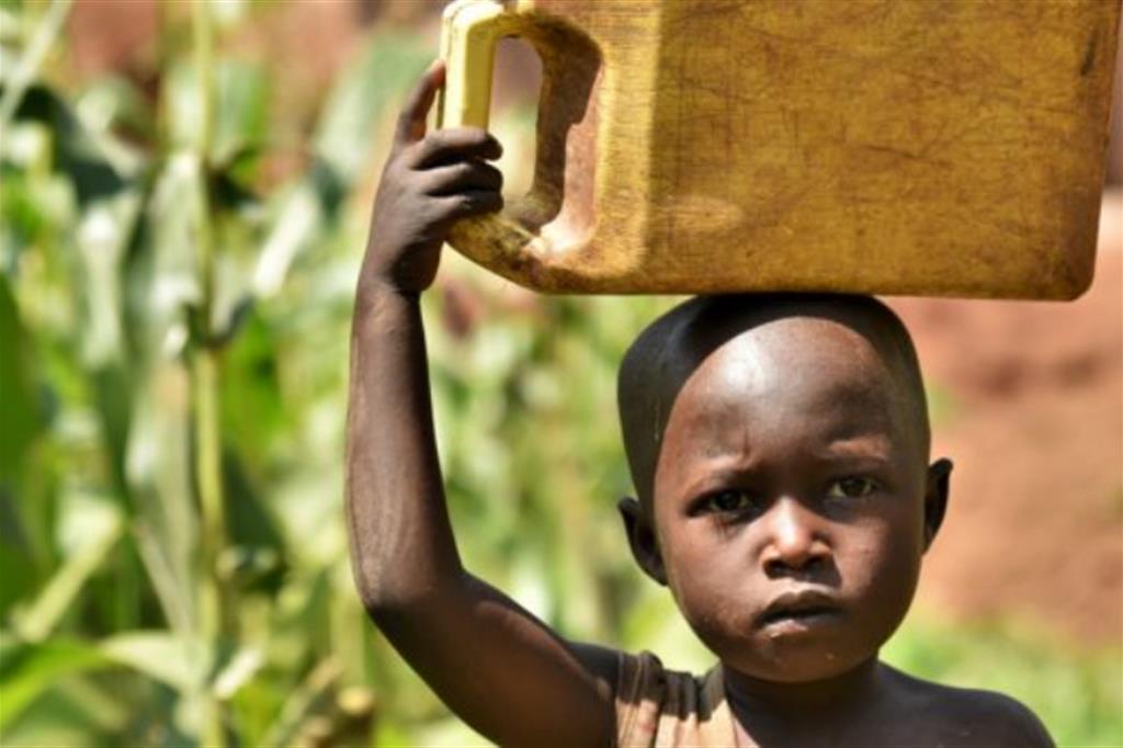 Un bambino porta una tanica da 20 litri di acqua sporca raccolta in un torrente nel fondovalle nel distretto di Gatsibo, in Ruanda 