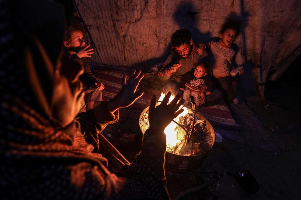 Una famiglia di rifugiati palestinesi si scalda al fuoco nel campo profughi di Khan Younis, nella Striscia di Gaza, in un'area molto povera nota come Nahr Al-Barid