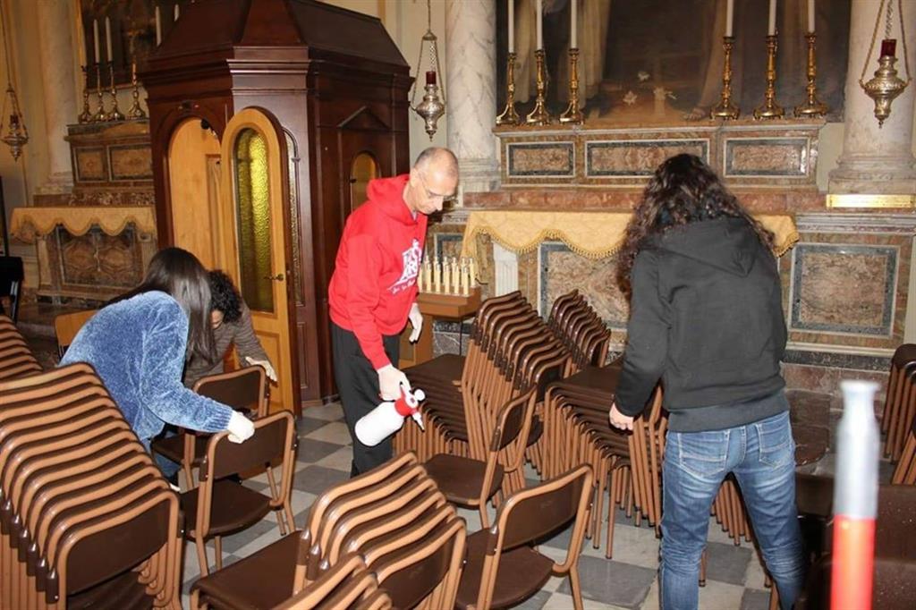 Monsignor Antonino Raspanti impegnato nella sanificazione delle sedie in cattedrale con altri volontari