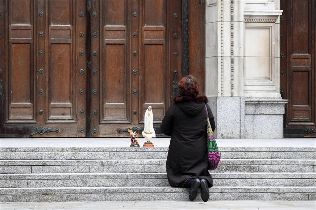 Una fedele in preghiera davanti alla Cattedrale di Westminster a Londra