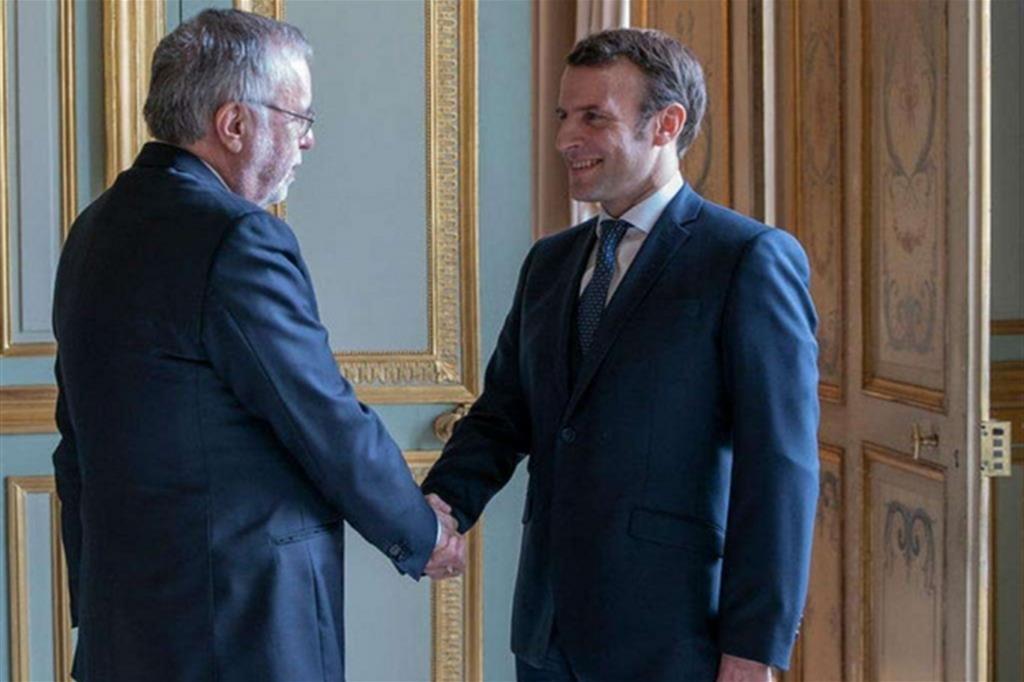 La stretta di mano all'Eliseo tra il presidente francese Emmanuel Macron e uno dei fondatori di Sant'Egidio, Andrea Riccardi