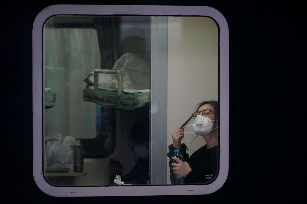 Una passeggera con una mascherina in partenza da Shanghai
