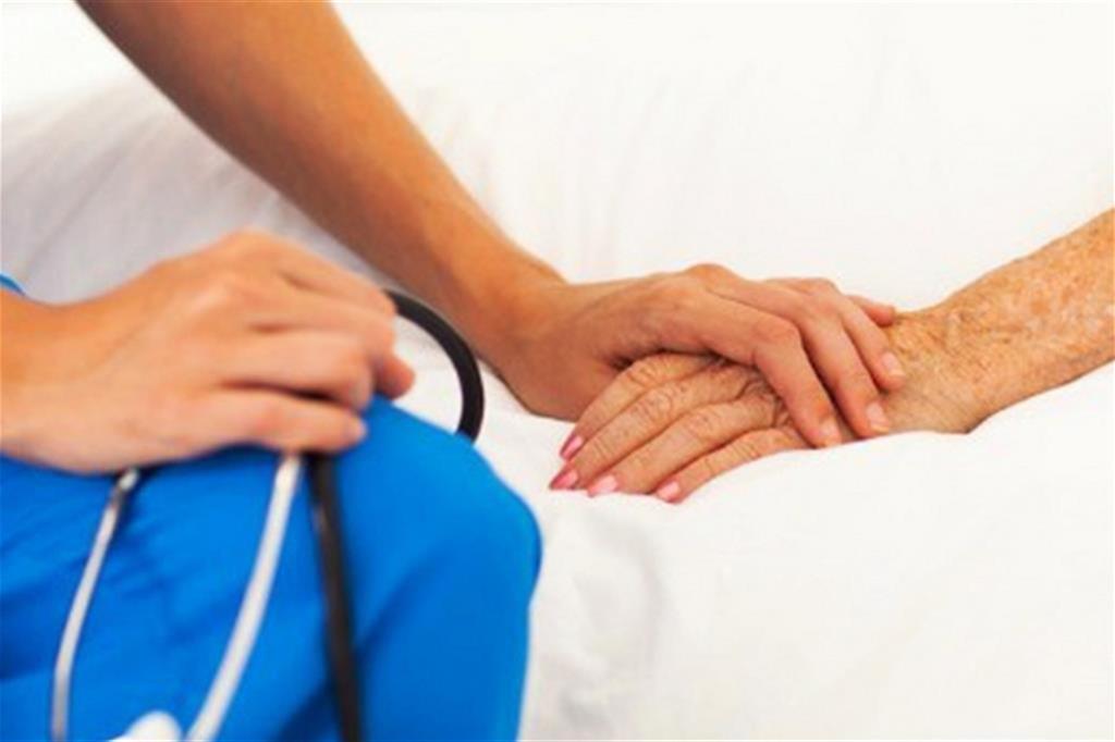 Un'infermiera conforta un'anziana