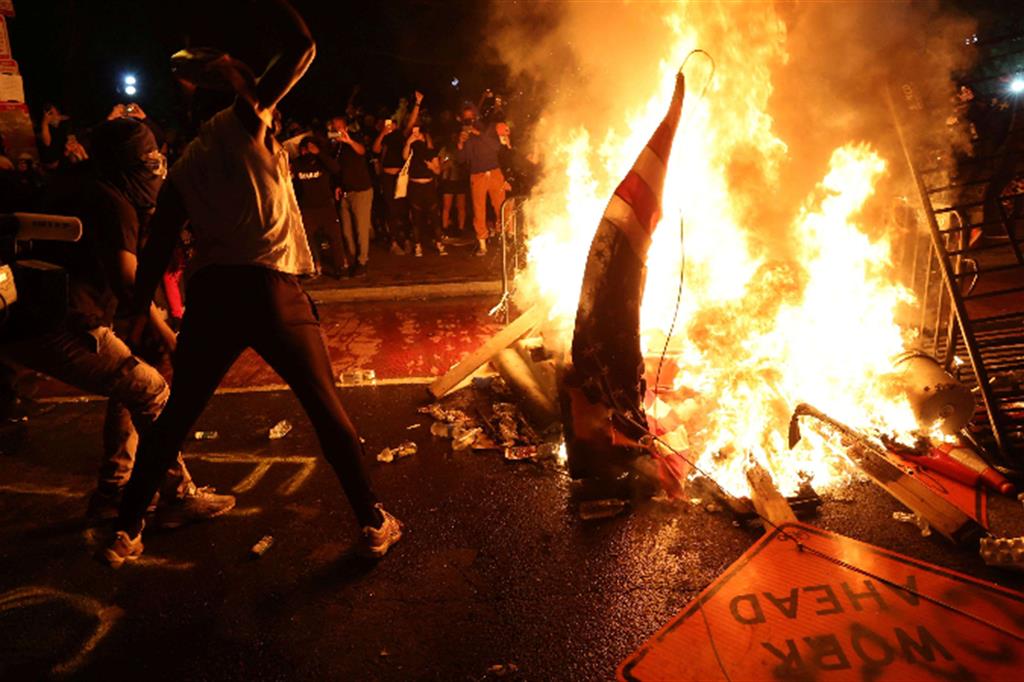 Manifestanti bruciano una bandiera americana a Minneapolis