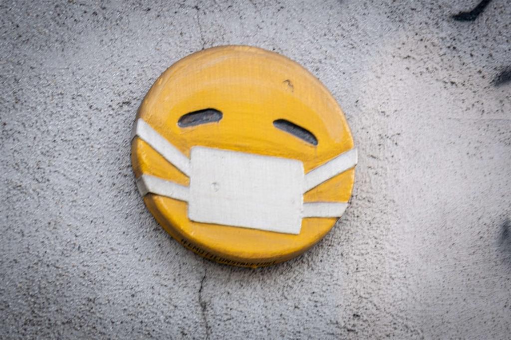 Un Emoticon con la mascherina in una strada di Milano