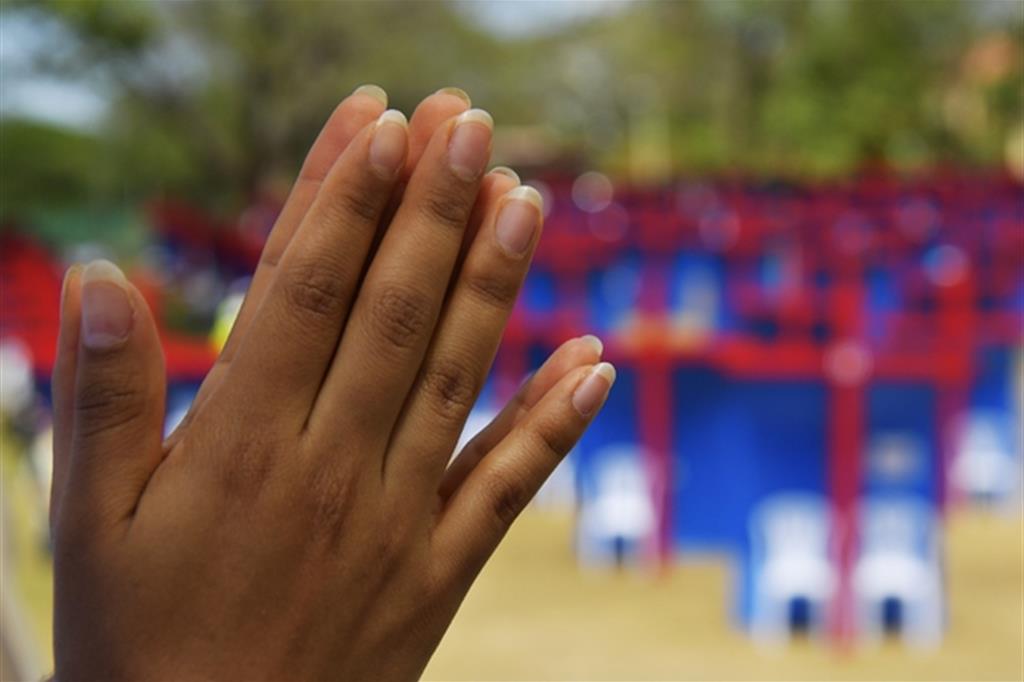 Mani in preghiera: sullo sfondo, i confessionali della Gmg di Panama