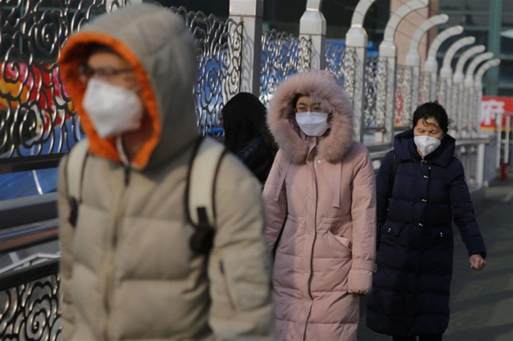 Alcuni passeggeri con la mascherina alla stazione di Pechino