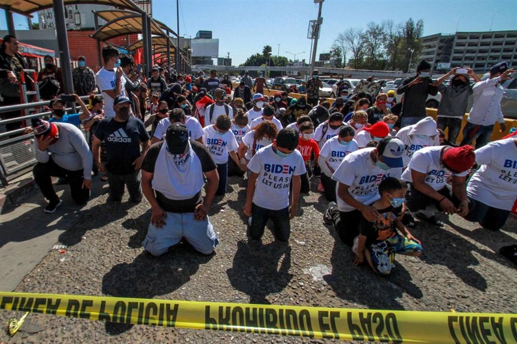 MIgranti implorano l'asilo in ginocchio a Tijuana