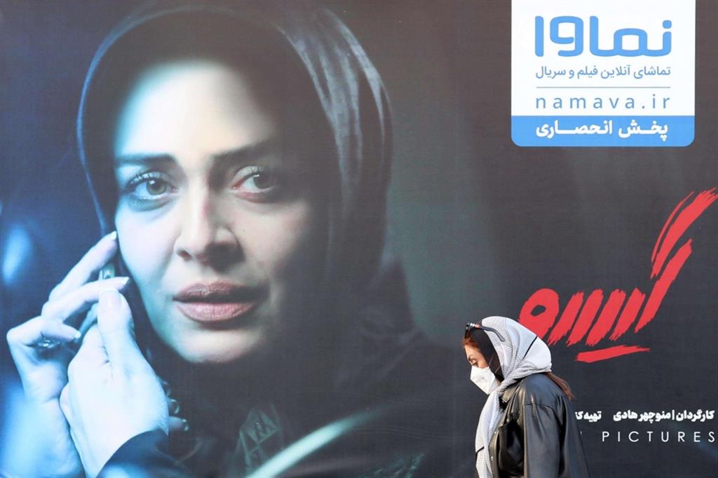 Una ragazza  davanti  al poster  di un film: da lunedì i cinema  a Teheran sono stati chiusi  per ordine delle autorità sanitarie