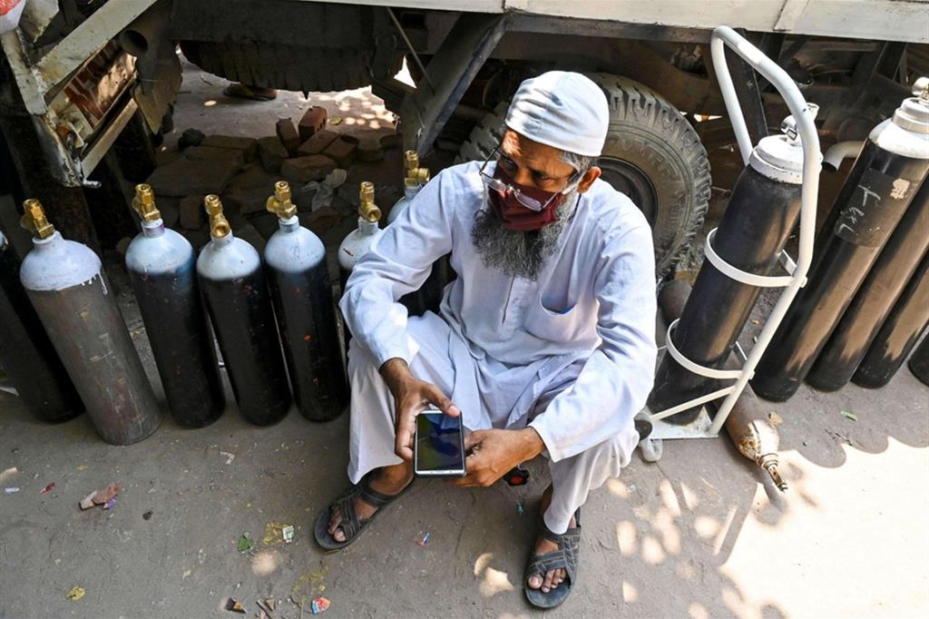 India, Nuova Dheli, un uomo attende di riempire bombole di ossigeno per malati di Covid-19