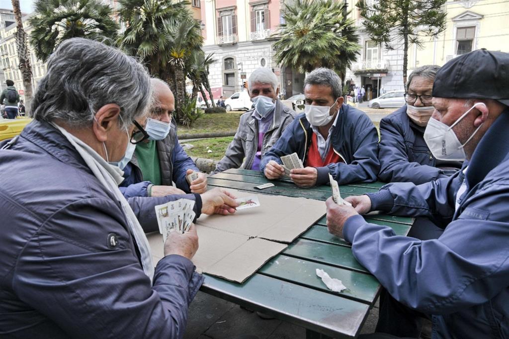 Meno contagi in Campania. Nei giardinetti di piazza Dante a Napoli un gruppo di persone, indossando mascherine anti covid,  giocano a Tressette