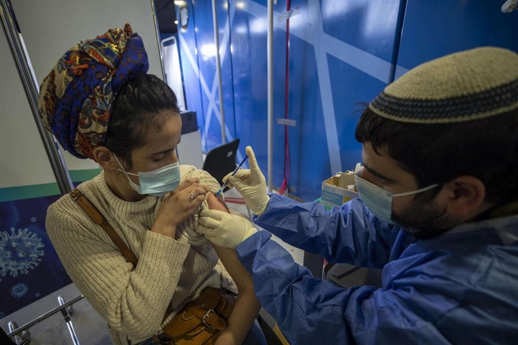 Una giovane donna viene vaccinata in un centro medico di Gerusalemme, in Israele