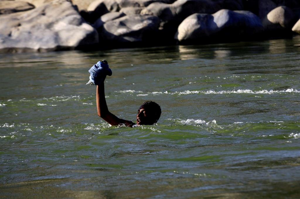 Un profugo etiope in fuga dai combattimenti nel Tigrai mentre fugge in Sudan attraversando il fiume Setit che segna il confine