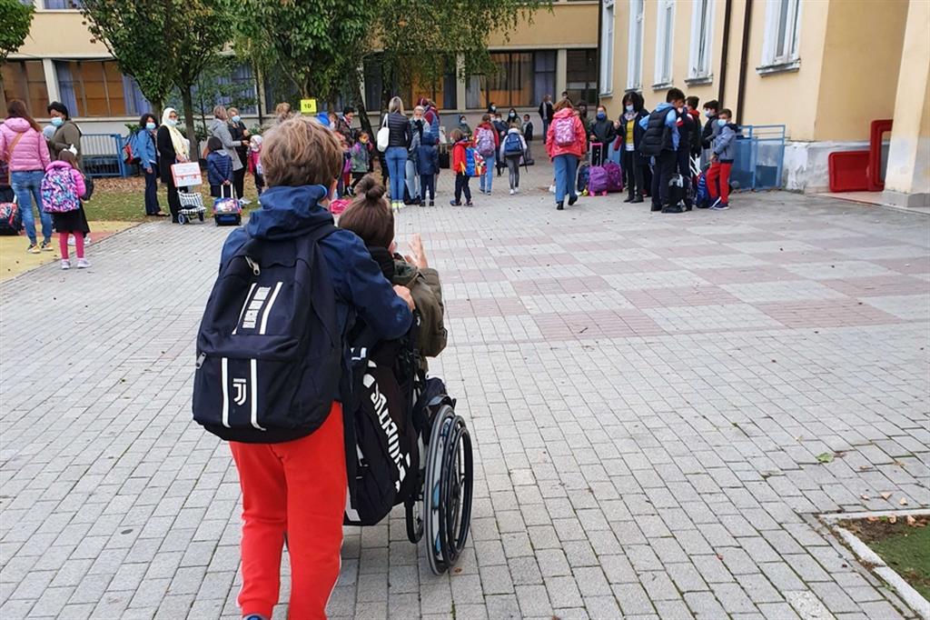 Luca va a scuola; la sua carrozzella è spinta da un alunno della sua classe