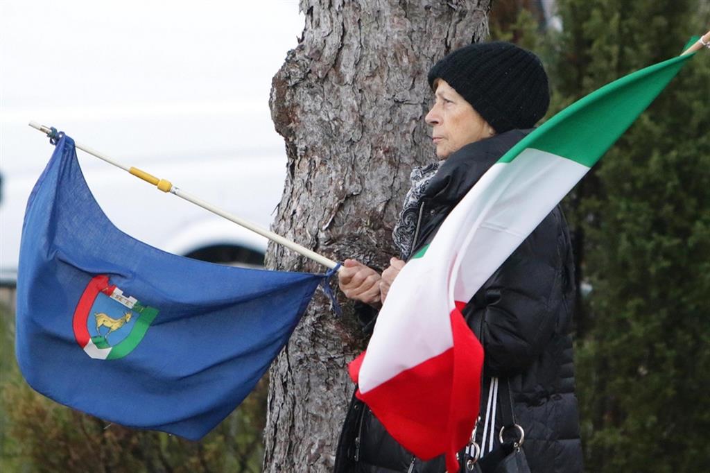 Una donna regge una bandiera dell'Istria e un Tricolore durante la cerimonia del Giorno del Ricordo alla Foiba di Basovizza, a Trieste 10 febbraio 2020