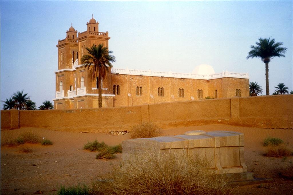 En primer plano, la Tumba de Charles de Foucauld en el cementerio cristiano de El Meniaa (antes El Golea) en Argelia, al fondo la iglesia de San Francesco no abierta al culto.