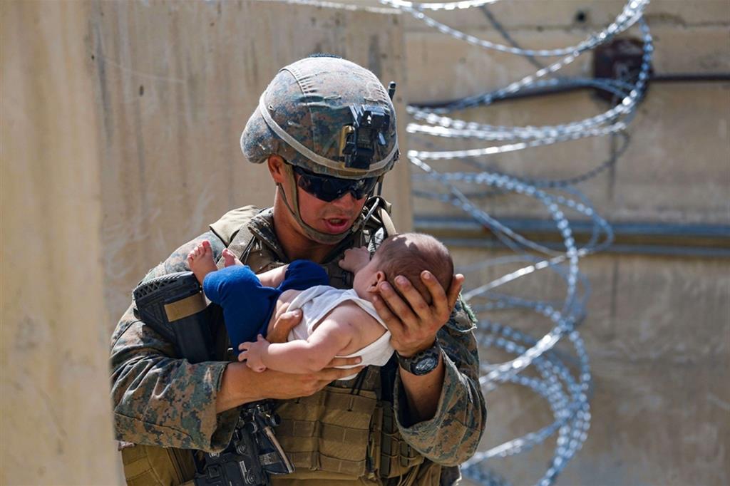 Un Marine americano con in braccio un neonato, in attesa di consegnarlo alla madre, all'aeroporto di Kabul
