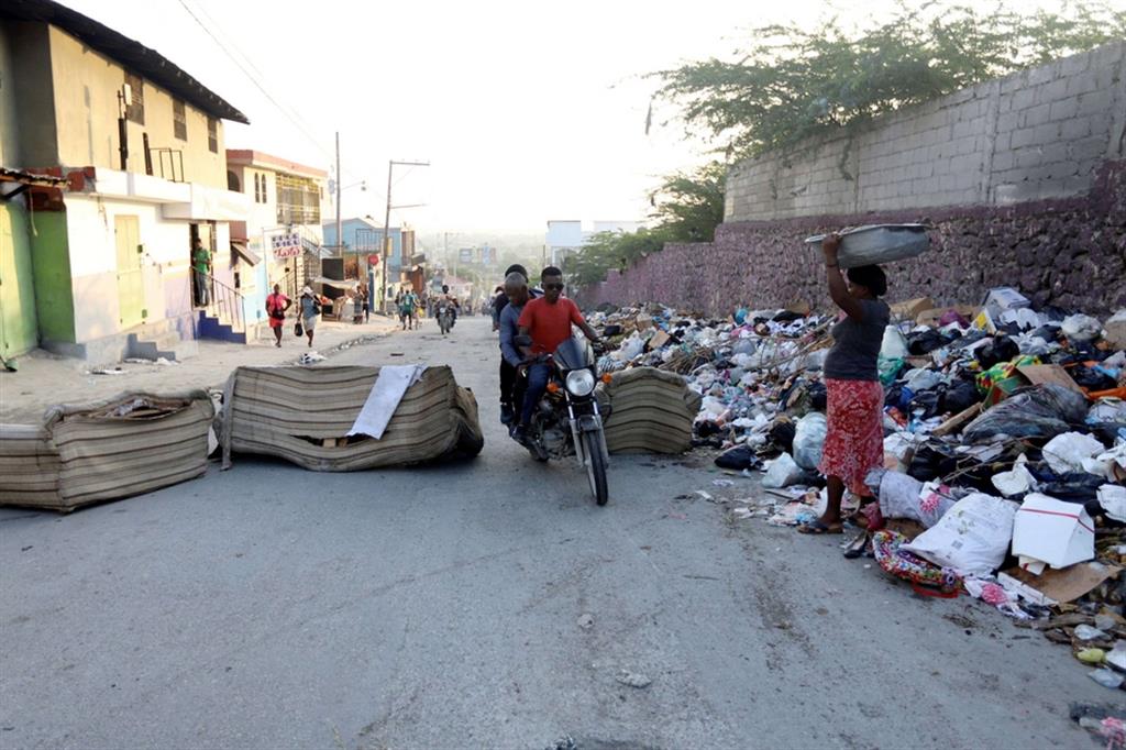 Un blocco stradale ad Haiti messo in atto per protesta contro i rapimenti dei missionari sull'Isola. Una moto fa lo slalom per superarlo