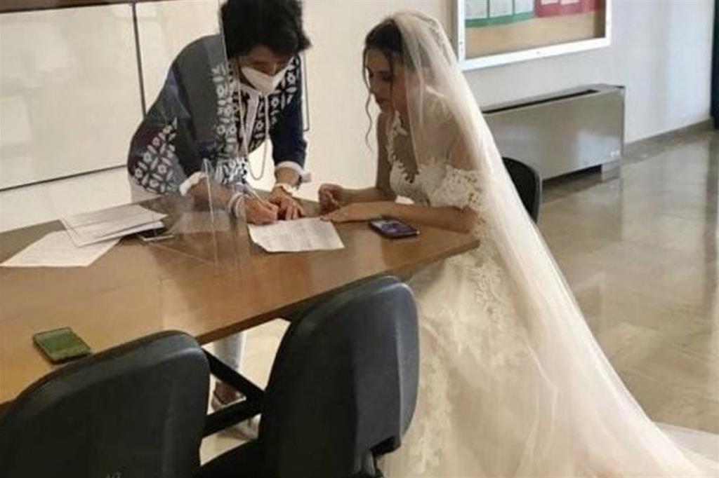 La foto dell'insegnante, in abito da sposa, mentre firma l'accettazione dell'incarico annuale