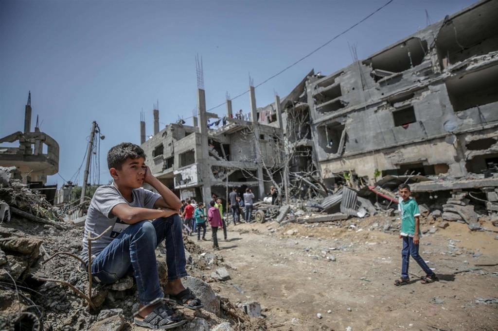 Un ragazzino palestinese siede sulle macerie di un palazzo distrutto a Gaza dai raid israeliani