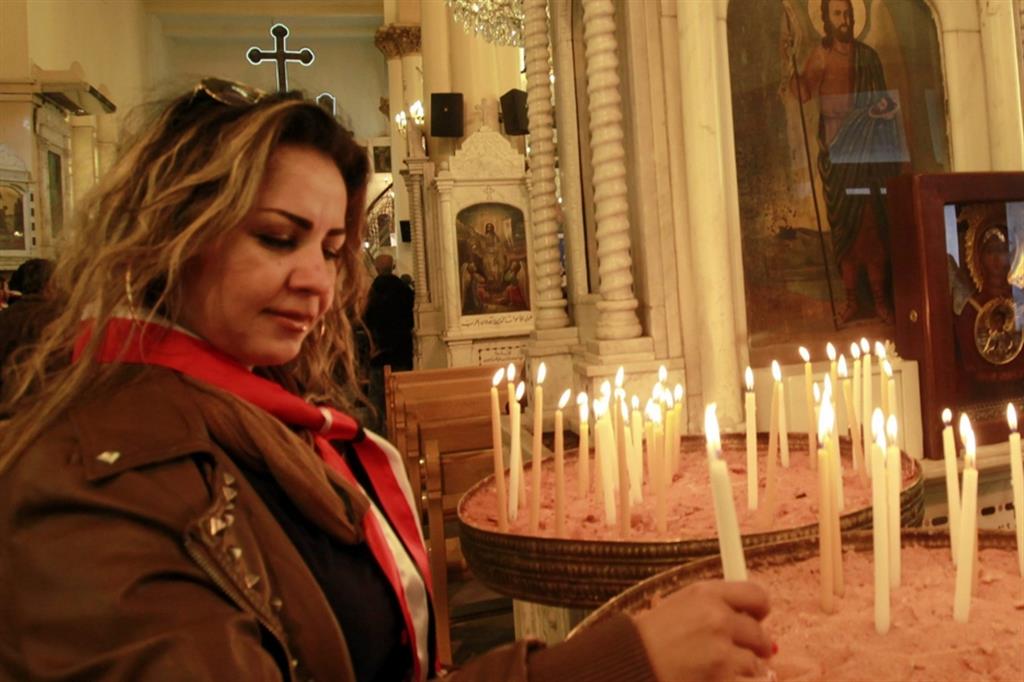 Una donna accende una candela nella chiesa della santa croce a Damasco