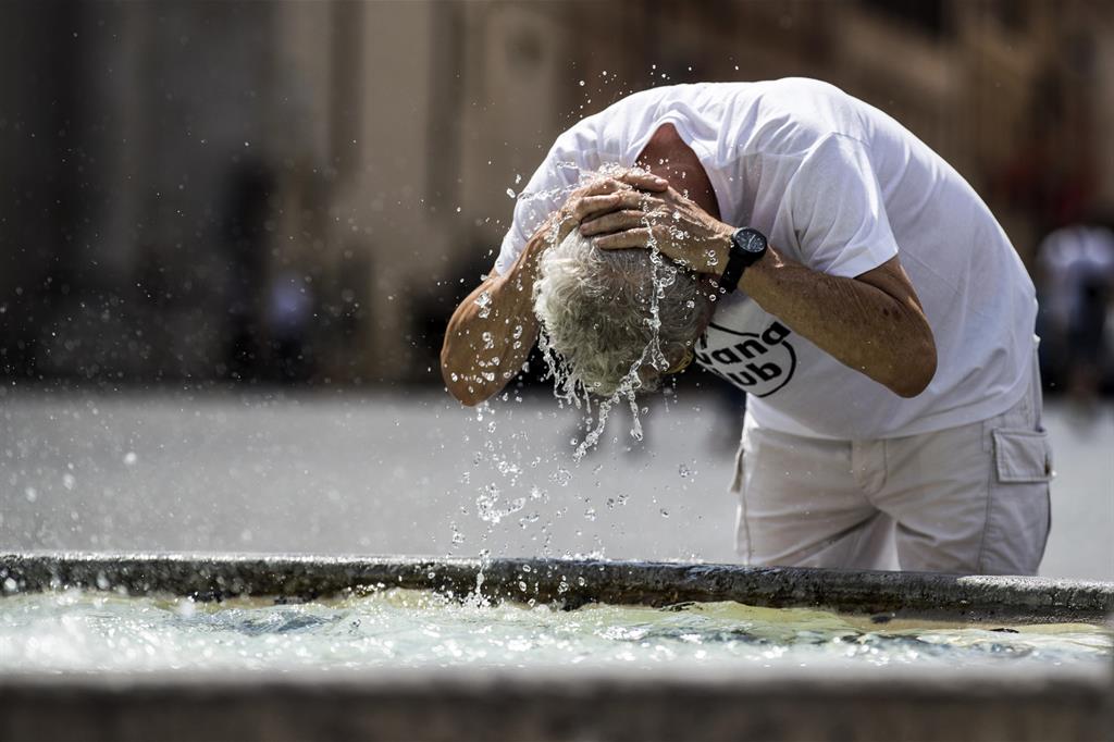 Una persona si rinfresca dal caldo nella fontana di piazza del Popolo, a Roma