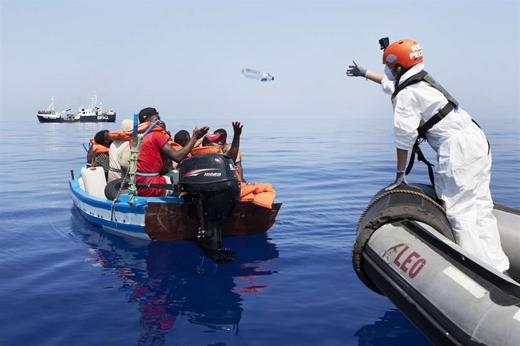 Un volontario della Resq People soccorre alcuni migranti a bordo di una barca