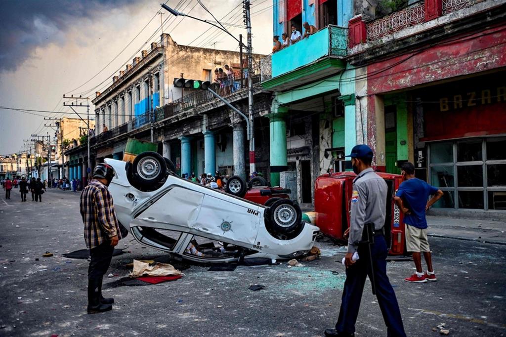Un’auto rovesciata dalla folla durante negli scontri di domenica nel centro della capitale l’Avana
