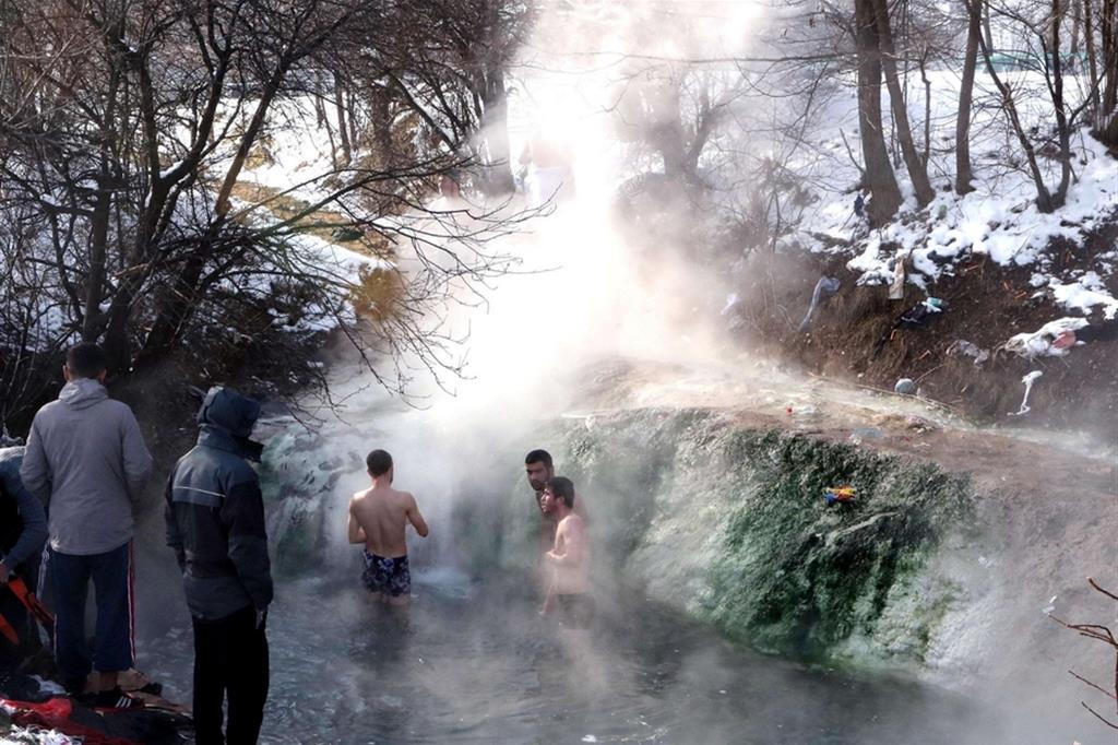 Migranti sulla rotta balcanica, qui in Bosnia, approfittano di una sorgente solfurea per lavarsi nonostante la neve