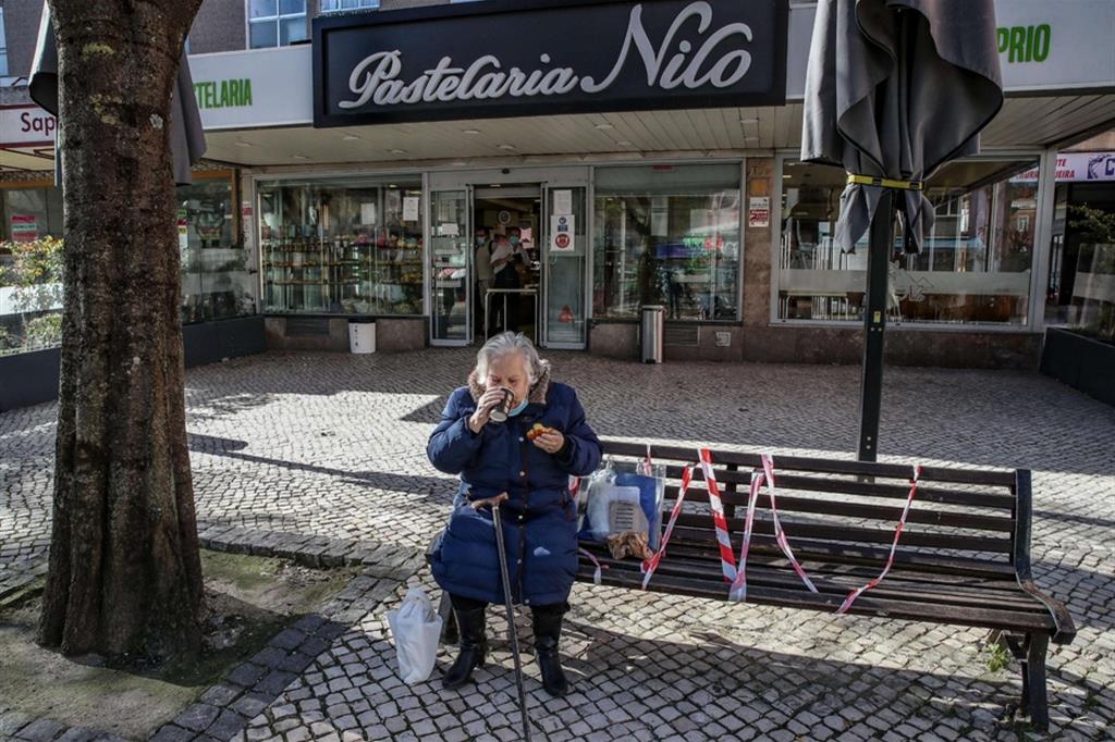 Lockdown sociale: un’anziana con un caffè d’asporto nel centro chiuso di Lisbona