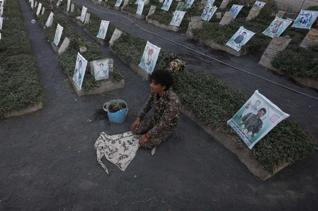 Un soldato yemenita prega per le vittime Huthi in un cimitero a Sana’a