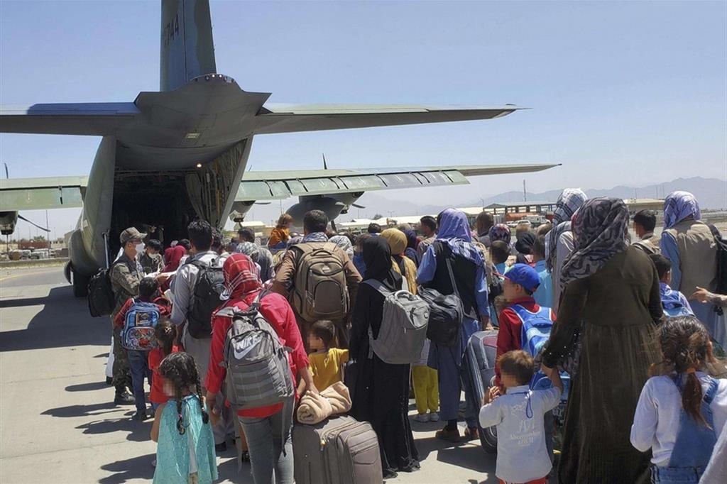 Intere famiglie afghane lasciano Kabul imbarcandosi su un aereo militare della Corea del Sud
