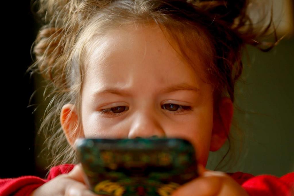 Una bambina guarda lo schermo di uno smartphone