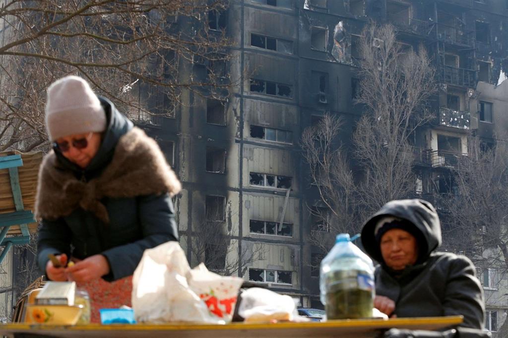 Due anziani residenti cucinano all'aperto fuori dal loro appartamento danneggiato a Mariupol (Ucraina 30 marzo)