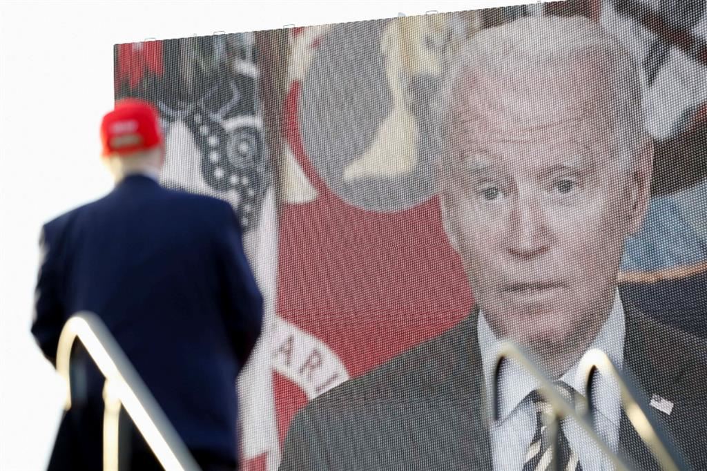 Joe Biden appare su un maxischermo mentro Donald Trump parla a un comizio contro di lui per le elezioni di midterm