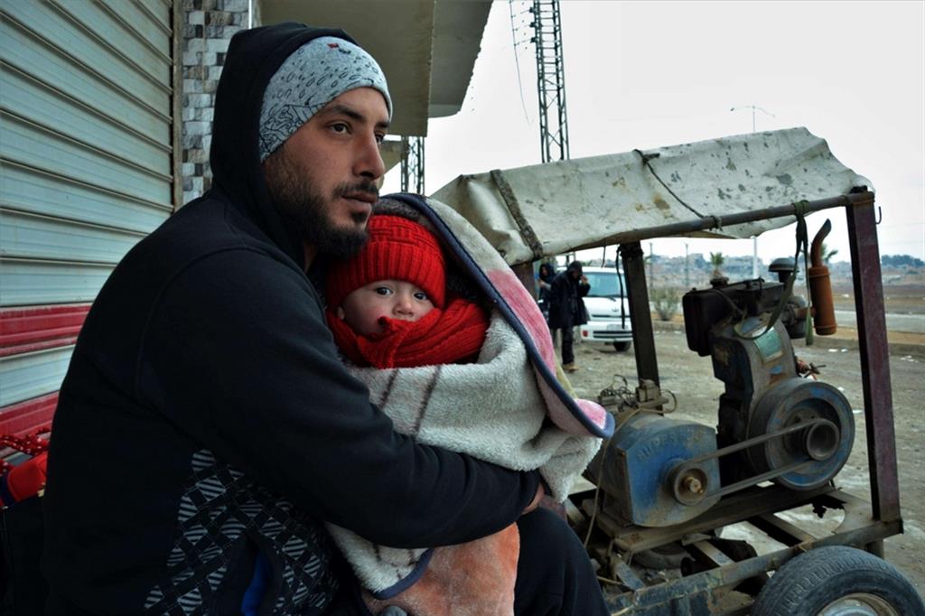 Un profugo siriano con in braccio il figlio nel Nord della Siria