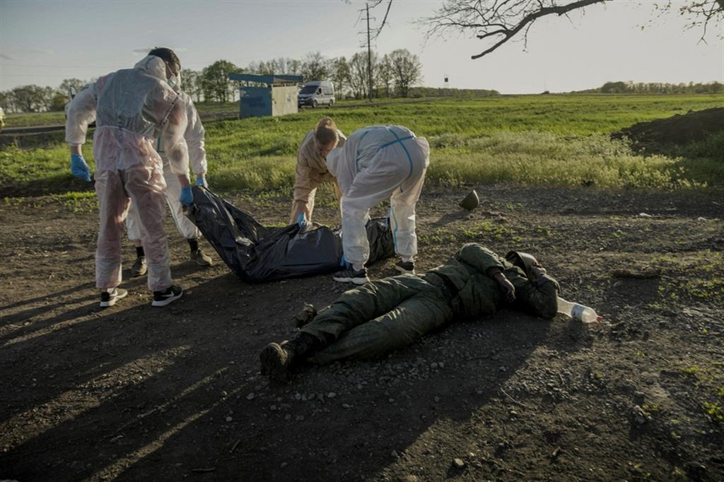 Volontari raccolgono i corpi di soldati russi caduti in combattimento trovati nel villaggio di Vilkhivka