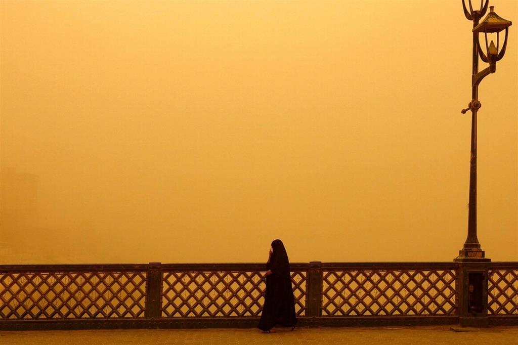 Una donna cammina su un ponte nel corso della tempesta di sabbia nella Capitale Baghdad
